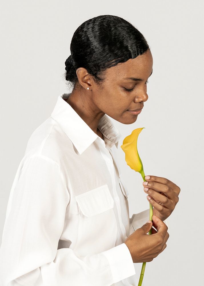 Black woman holding a yellow calla lily flower with care