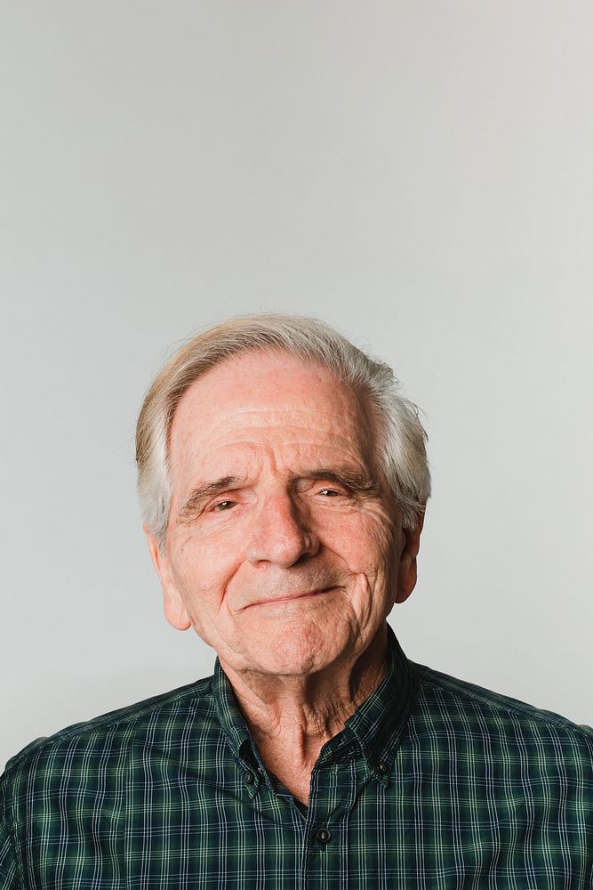 Elderly Caucasian man with white hair smiling on gray background