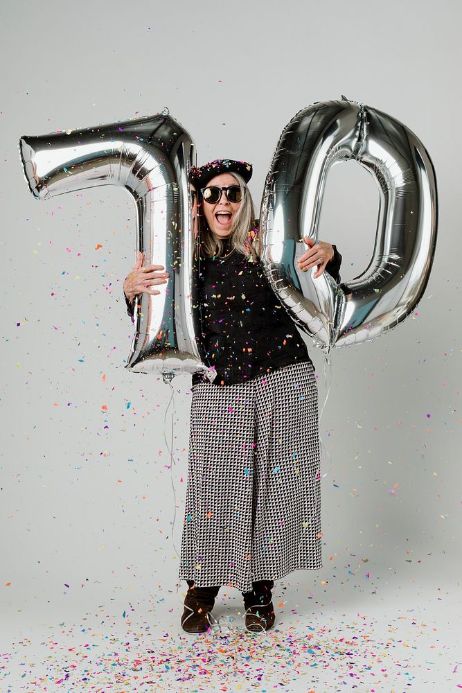 Senior woman holding silver balloons for 10 years celebration