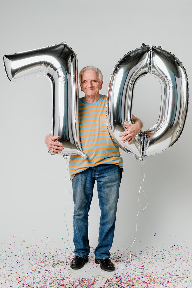 Senior man holding silver balloons for 70 years celebration