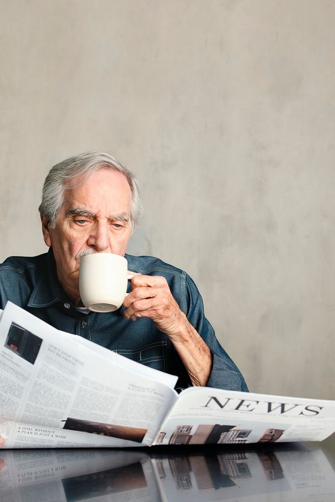 Senior man reading the newspaper and drinking coffee