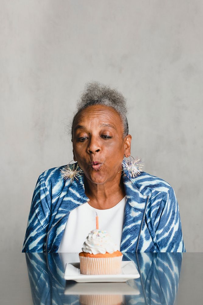 Senior woman blowing a candle on a cake on her birthday celebration