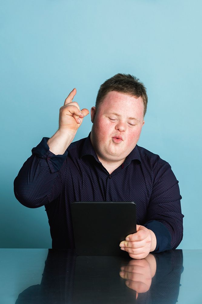Cute boy with down syndrome homeschooling using a digital tablet during the coronavirus pandemic 