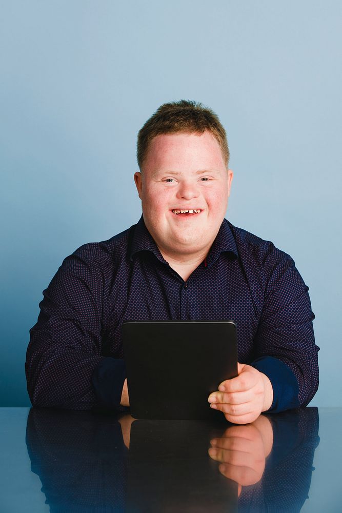 Cute boy with down syndrome homeschooling using a digital tablet during the coronavirus pandemic 