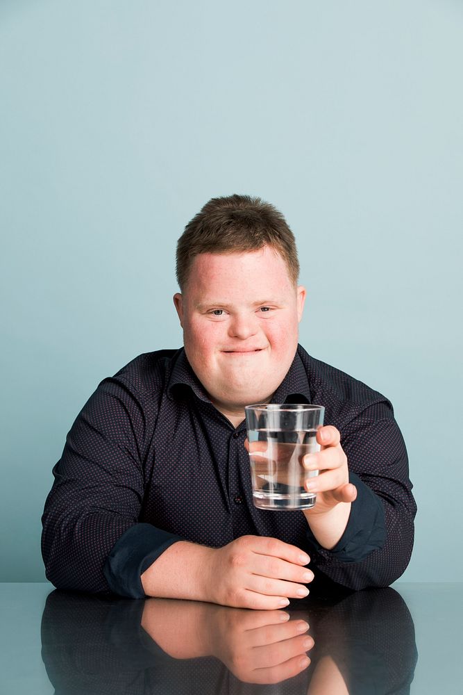 Cute boy with down syndrome holding a glass of water 