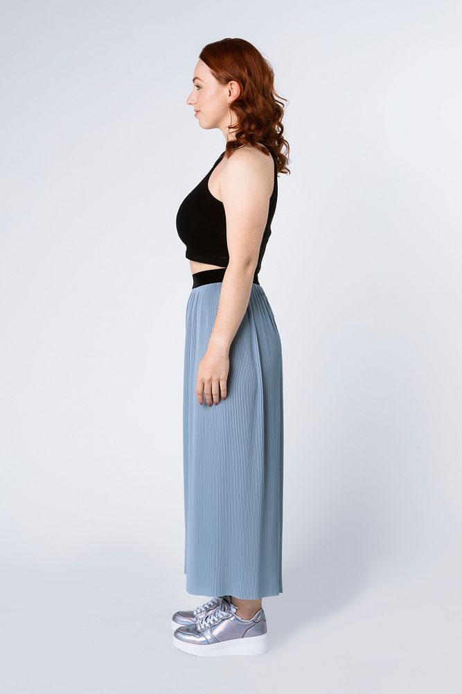 Woman wearing a crop top and skirt pants in a profile shot 