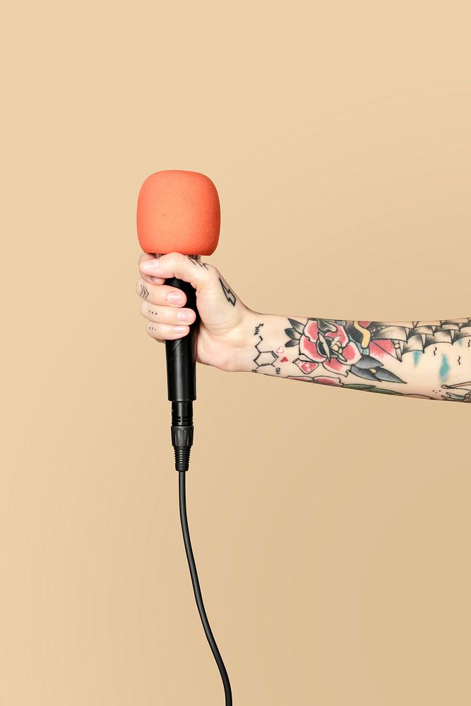 Hand holding a microphone with cream background