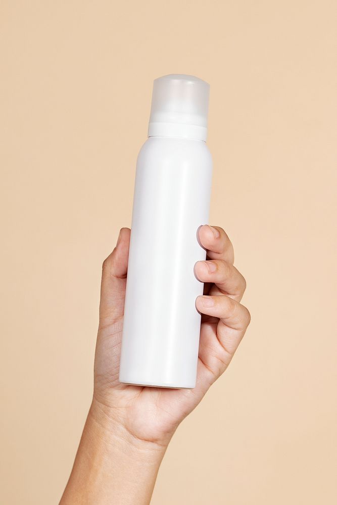 Caucasian woman holding a white blank spray bottle