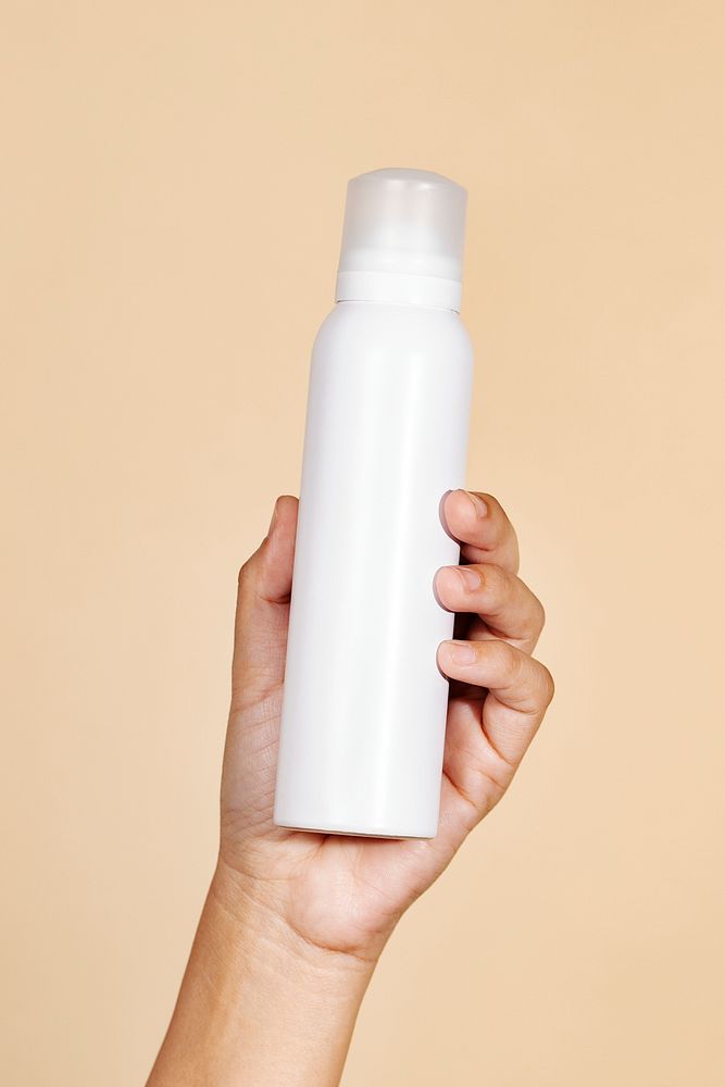 Hand holding a white spray bottle mockup