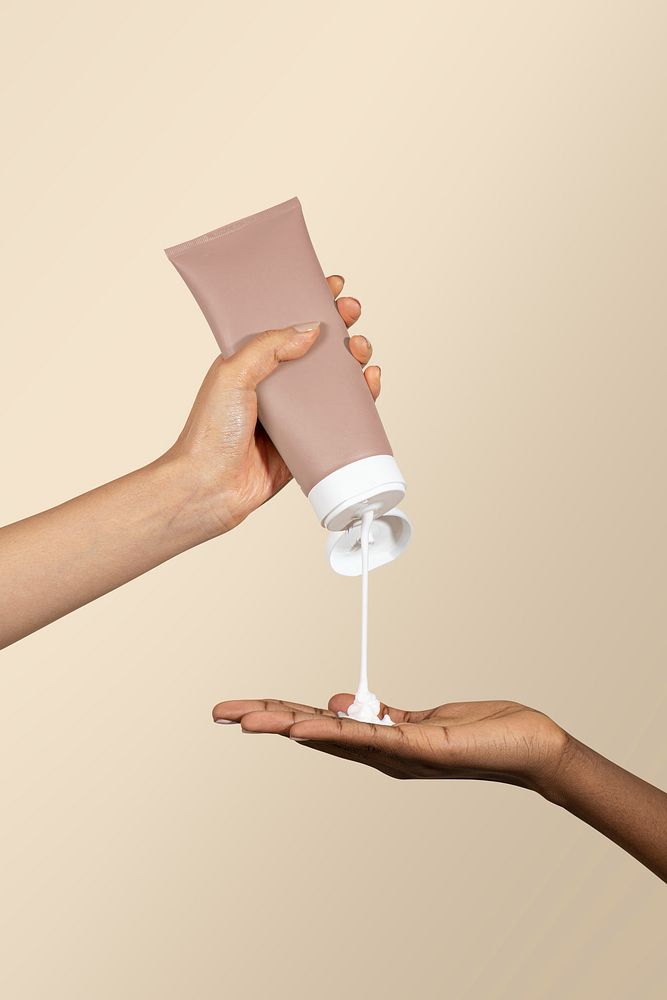 Woman squeezing cream from an unlabeled beige tube