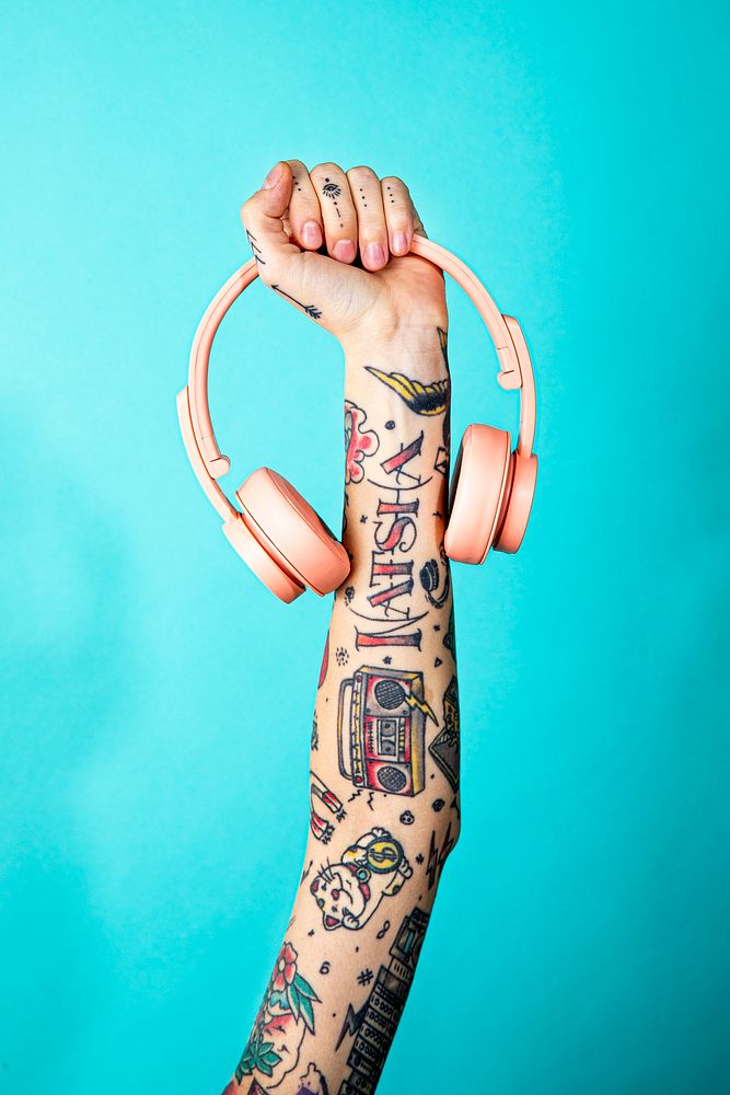 Tattooed arm holding a pink headphones