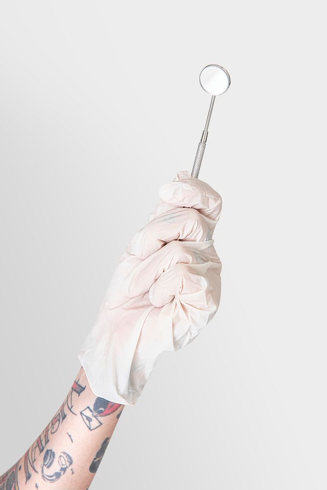 Tattooed hand in a white glove holding a dentist's mirror