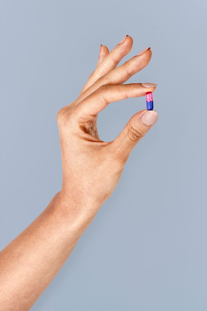 Hand holding a pink and blue pill mockup