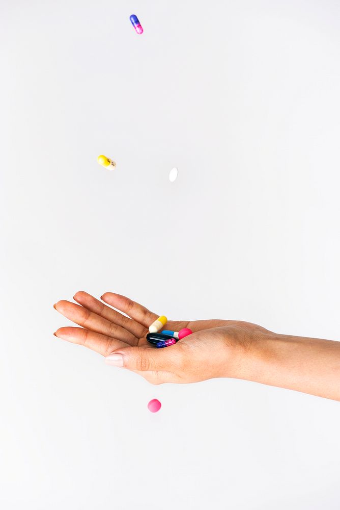 Colorful pills falling from above to a palm