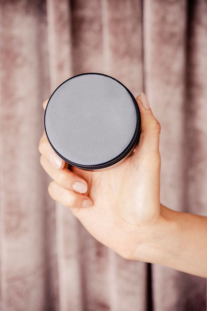 Hand holding face cream jar mockup