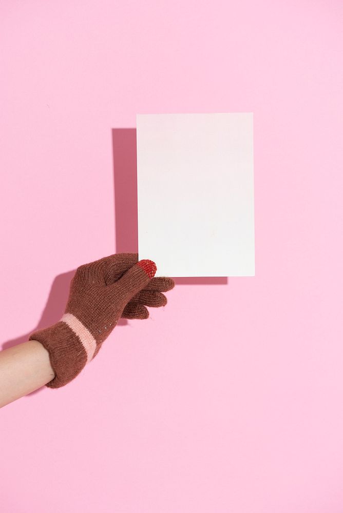 Hand wearing glove holding a paper with pink wall