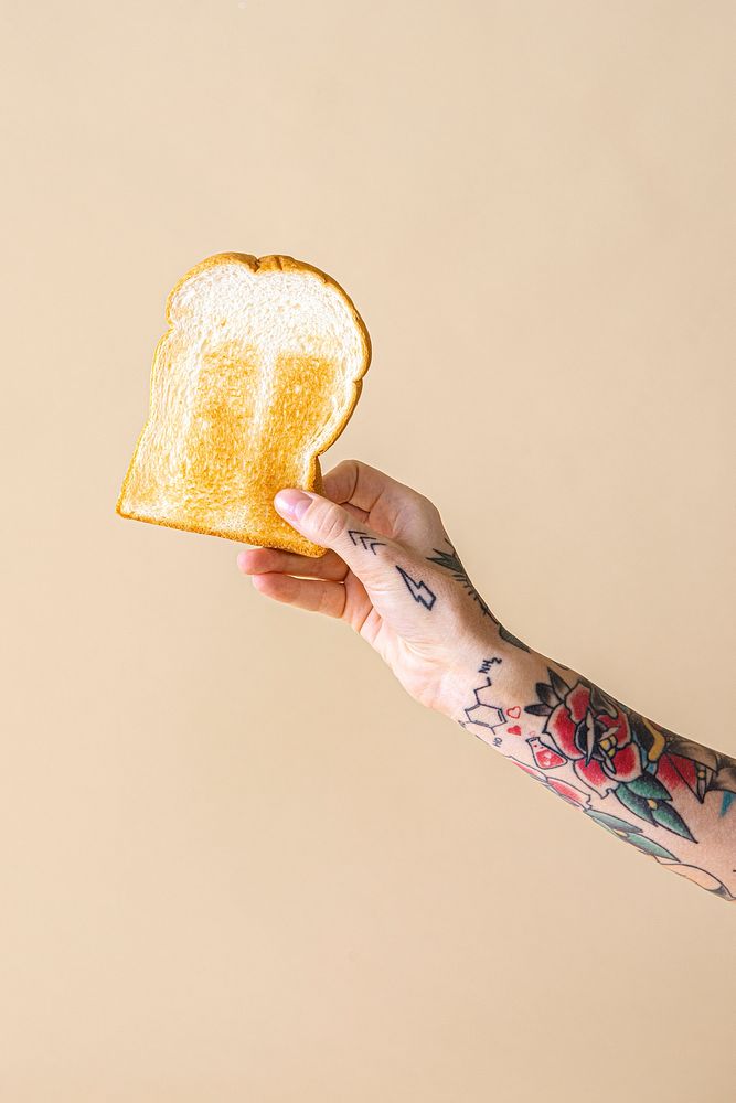 Hand with tattooed holding toasted bread