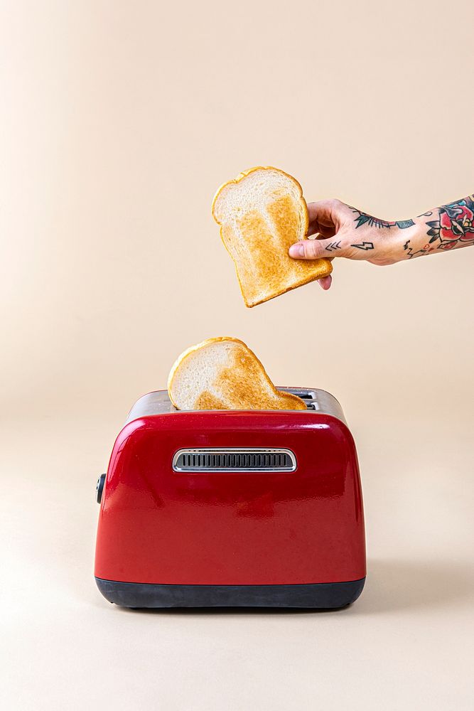 Hand holding bread popping up from a red toaster