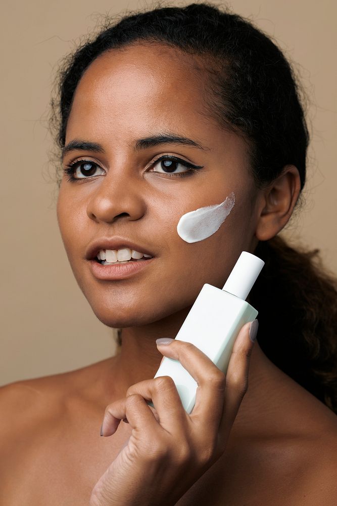Beautiful African American woman holding a facial cream container