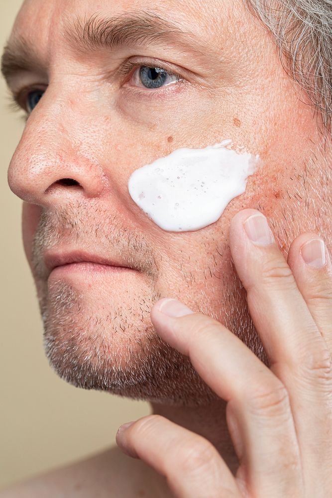 Closeup of a senior man using a moisturizing cream for skincare routine