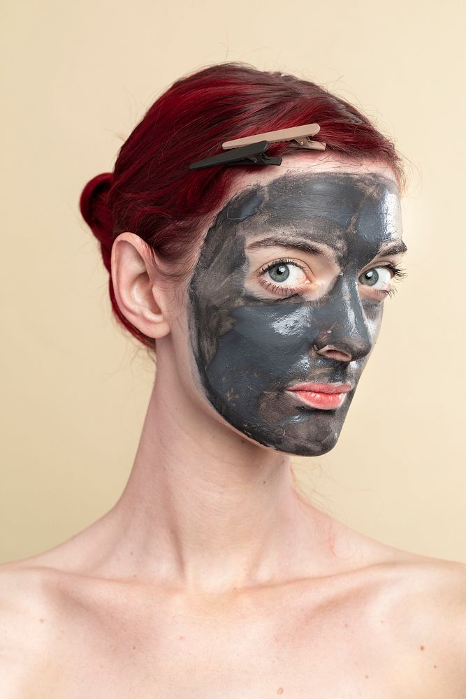 Beautiful woman wearing an activated black charcoal mask for facial treatment