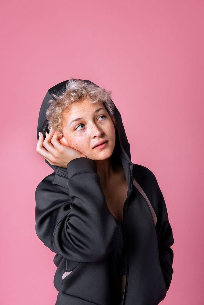 Studio portrait of a cute blonde girl wearing black hoodie and headphones