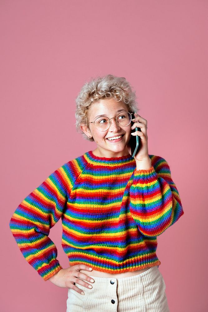 Cute cheerful girl in a rainbow sweater and a green beret talking on the phone