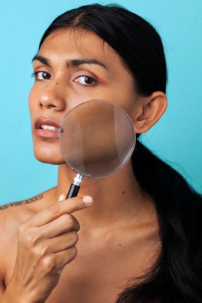 Woman using a magnifying glass to check her skin