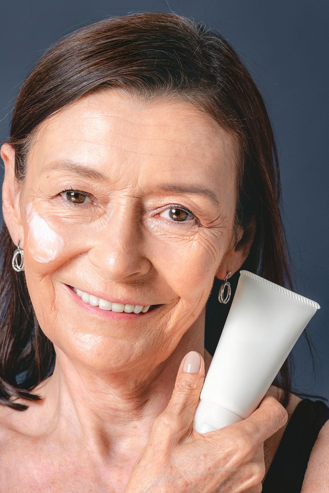 Senior woman holding a white face cream tube