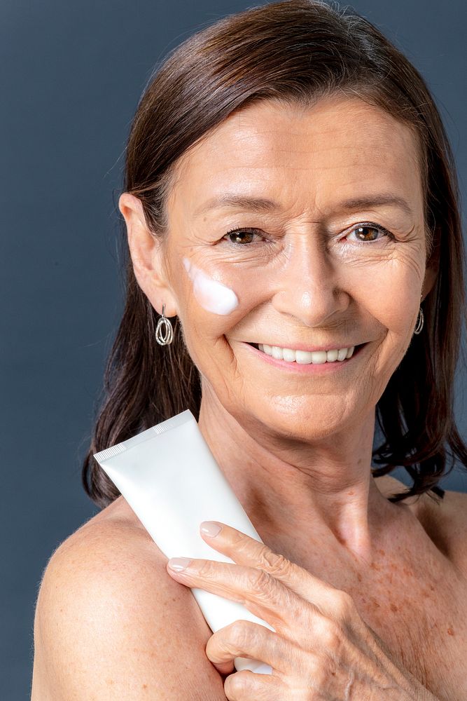 Senior woman holding a white face cream tube