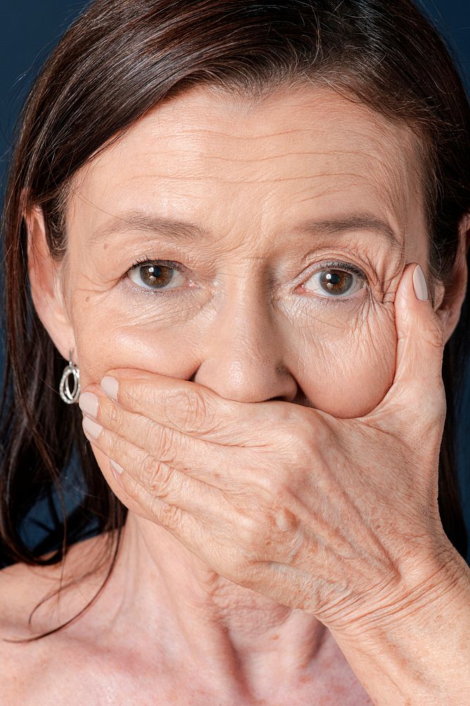 Close up of senior woman covering her mouth