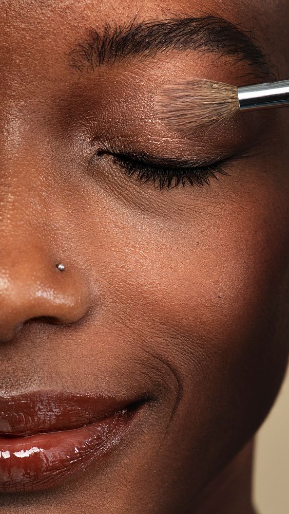Makeup artist applying eye shadow on a black woman