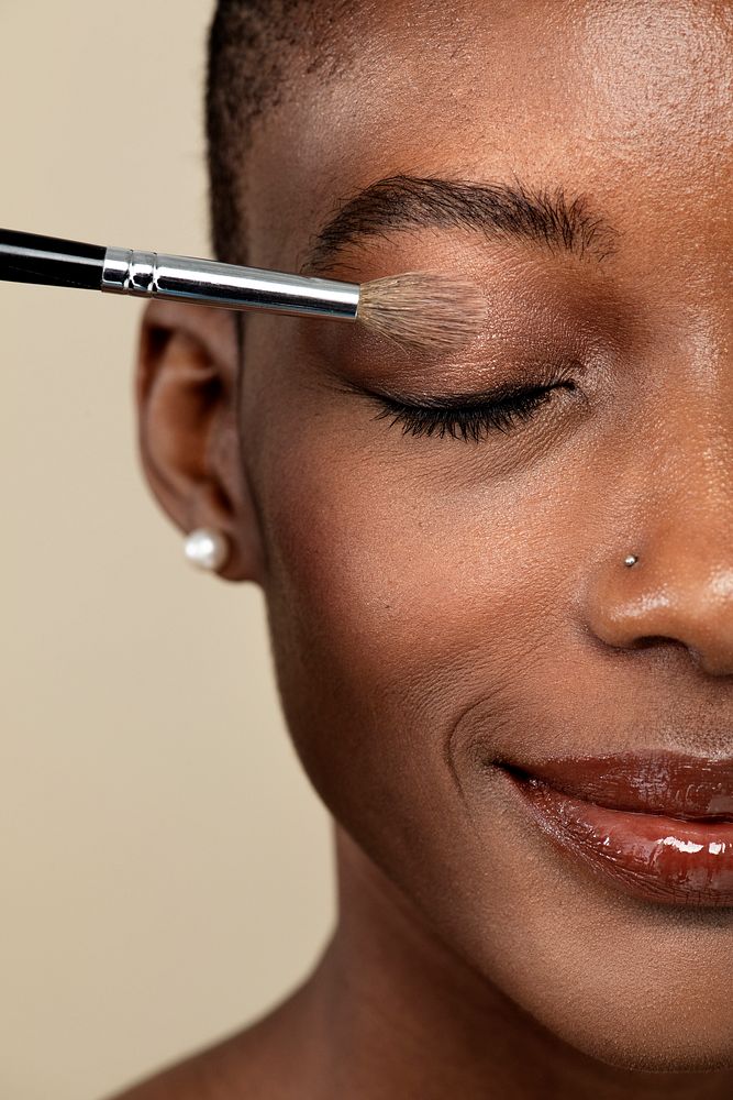 Makeup artist applying eye shadow on a black woman