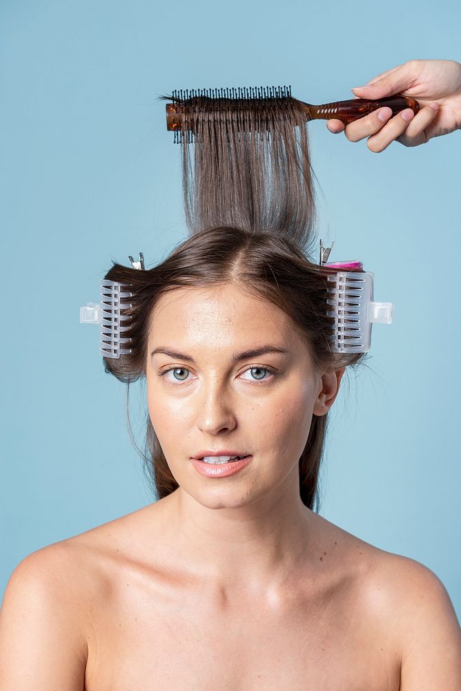 Young woman using hair curlers