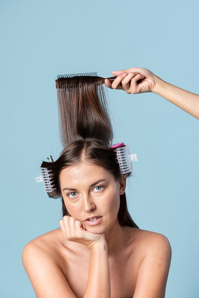 Young woman using hair curlers 