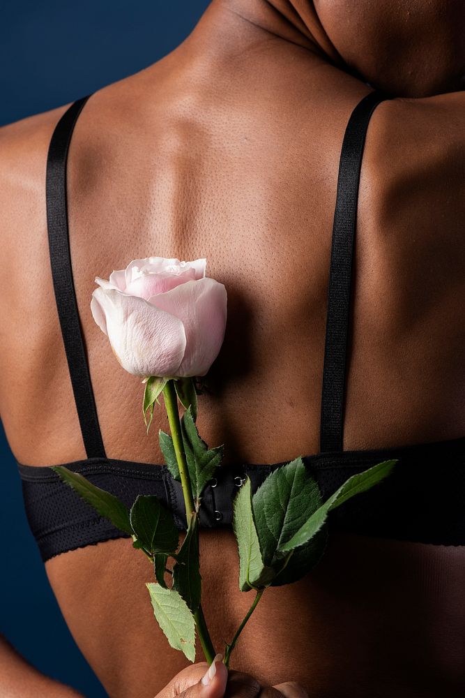 Woman holding a pink rose behind her back