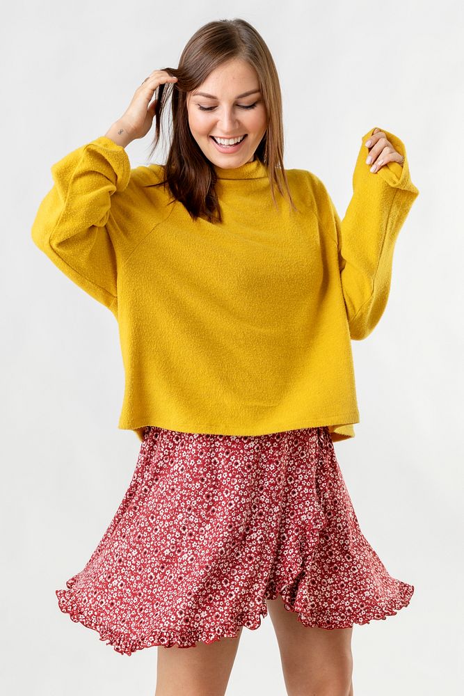 Cheerful woman wearing a mustard yellow sweater on a red flower dress