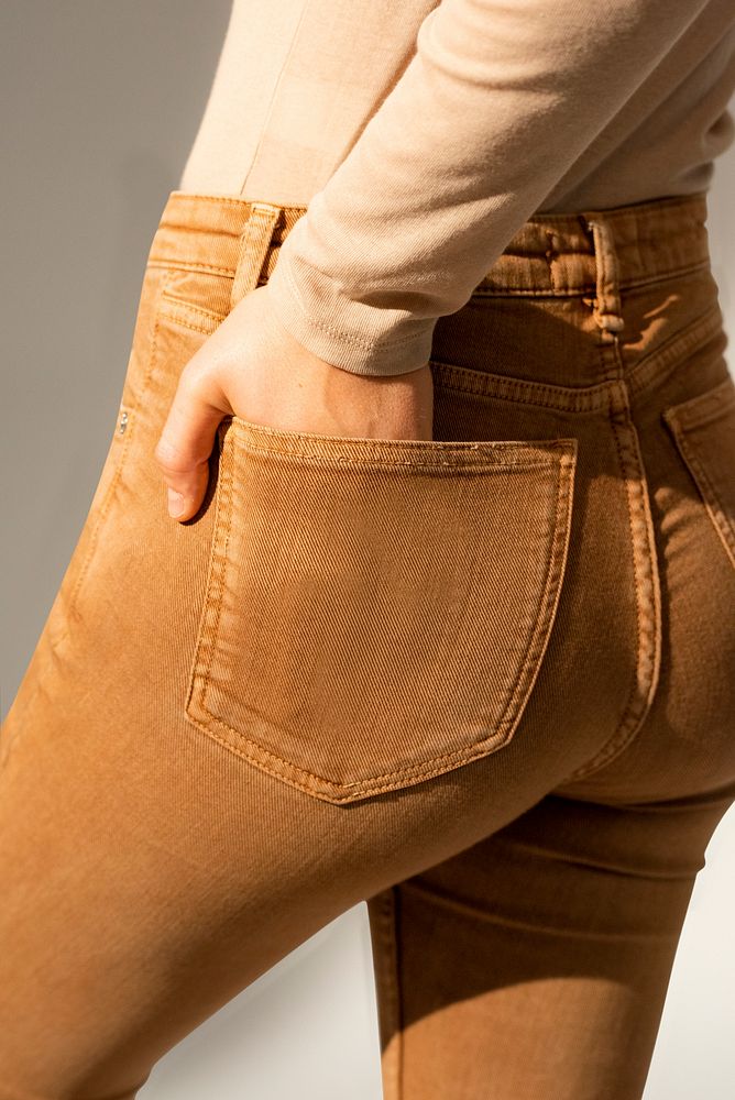 Woman in brown jeans with hand tucked in pocket rear view fashion photoshoot