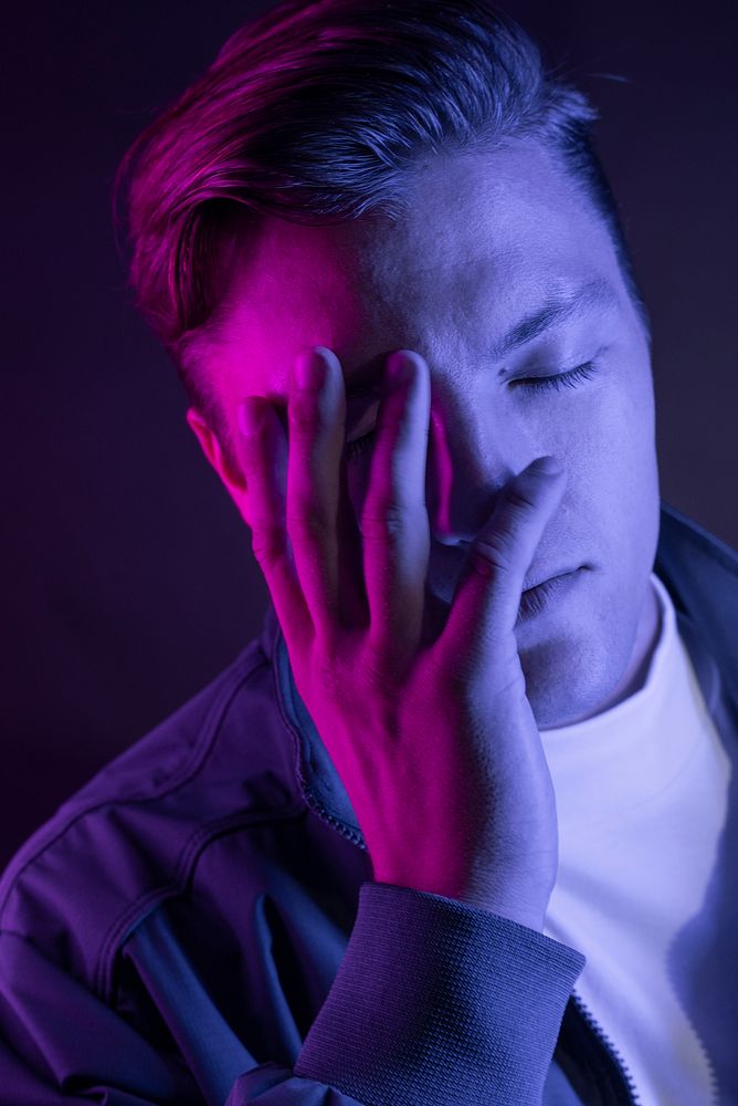 Man having a headache with purple light portrait