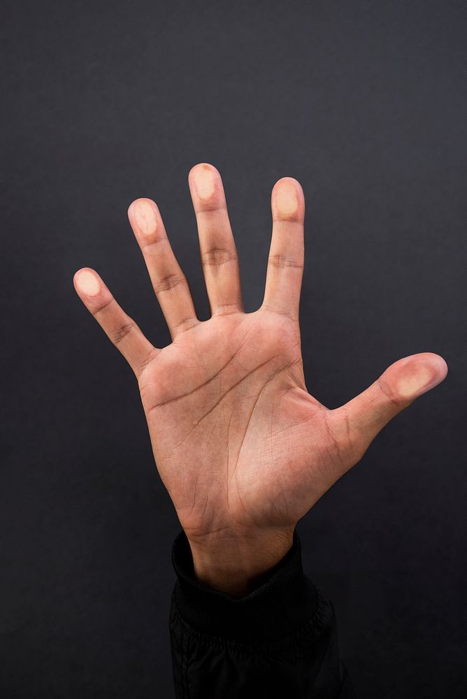 Hand showing palm gesture with black long sleeve