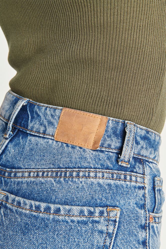 Woman wearing blue jeans with a brown tag 
