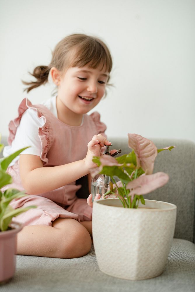 Kid watering potted plants at home 