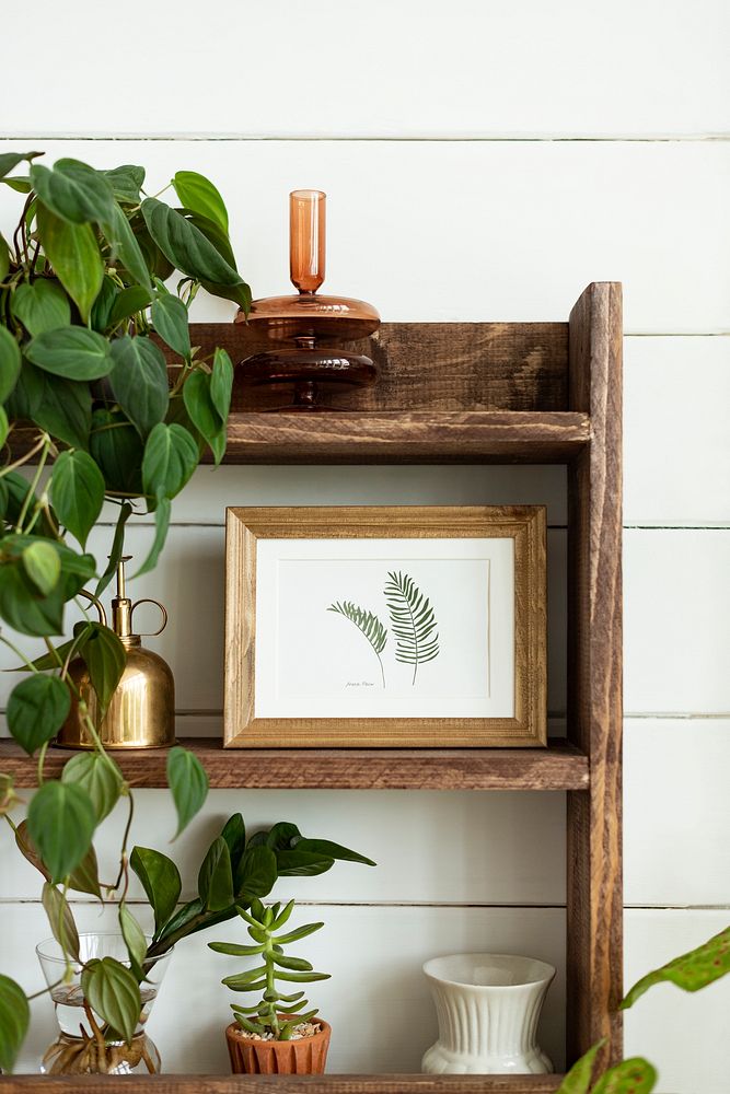 Picture frame mockup psd on wooden shelf with houseplants home decor