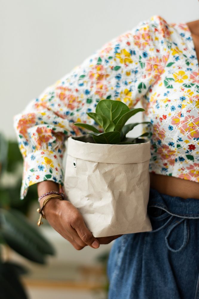 Woman holding houseplant in eco-friendly paper bag