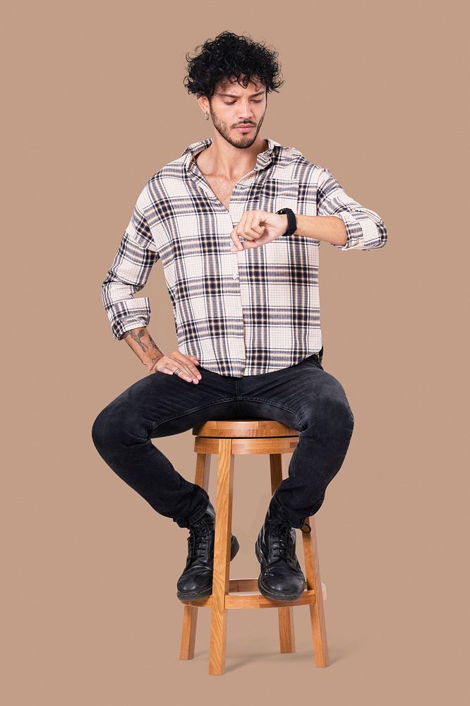 Latin man sitting mockup psd on a stool while checking the time