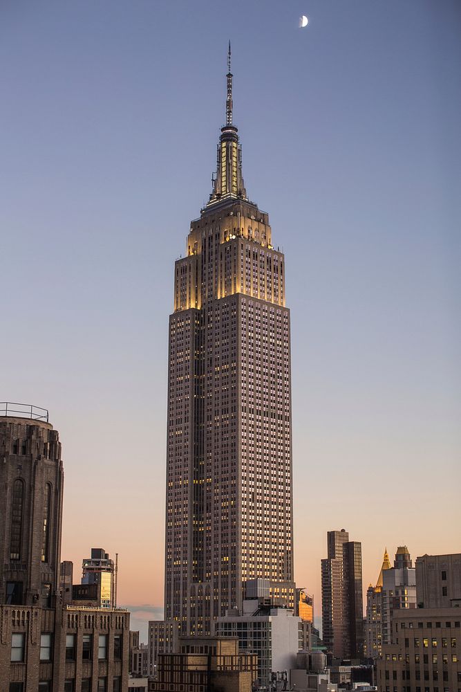 A skyscraper in New York City at dusk with the moon in the sky. Original public domain image from Wikimedia Commons