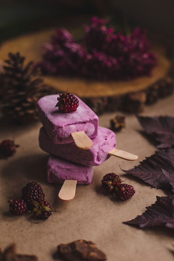 Pink loganberry popsicles on a table with dried leaves and pinecones. Original public domain image from Wikimedia Commons