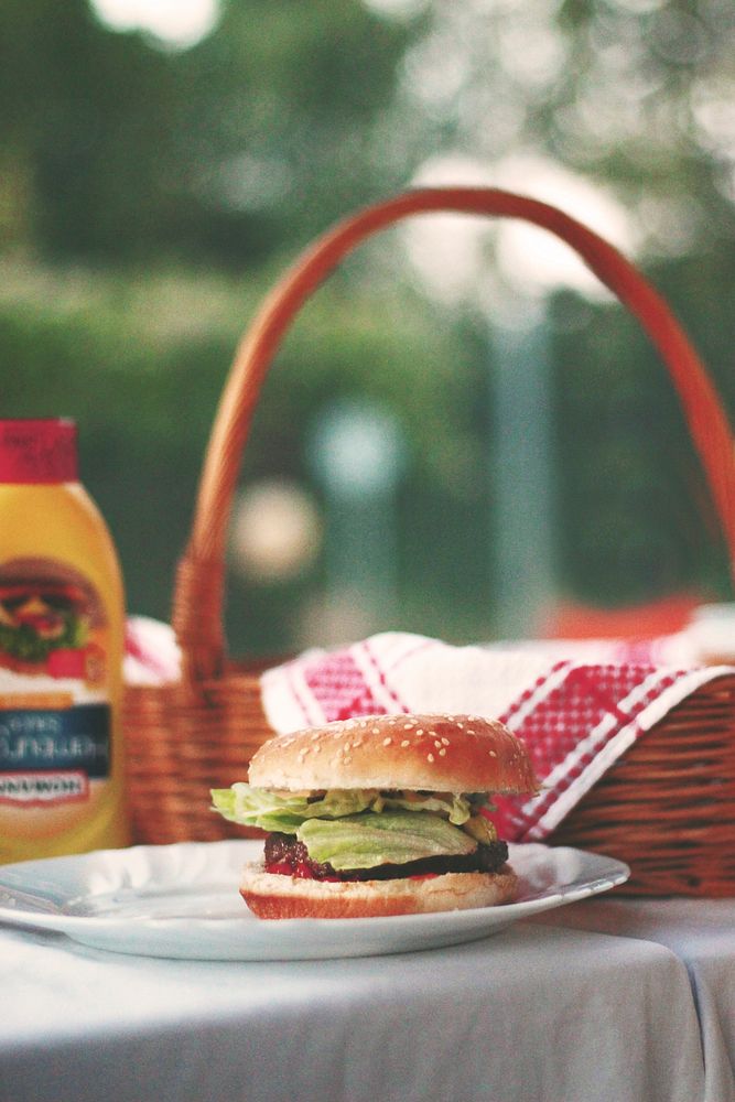American hamburger on a picnic table by a basket. Original public domain image from Wikimedia Commons