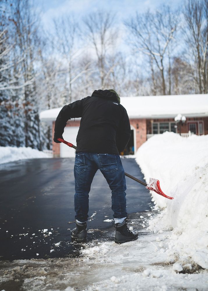 A man shoveling snow off his driveway in Muskoka. Original public domain image from Wikimedia Commons
