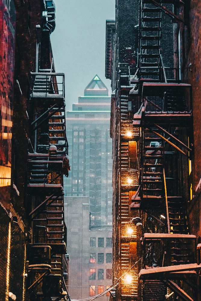 View through an alley of apartment stairwells of a skyscraper downtown in the winter. Original public domain image from…